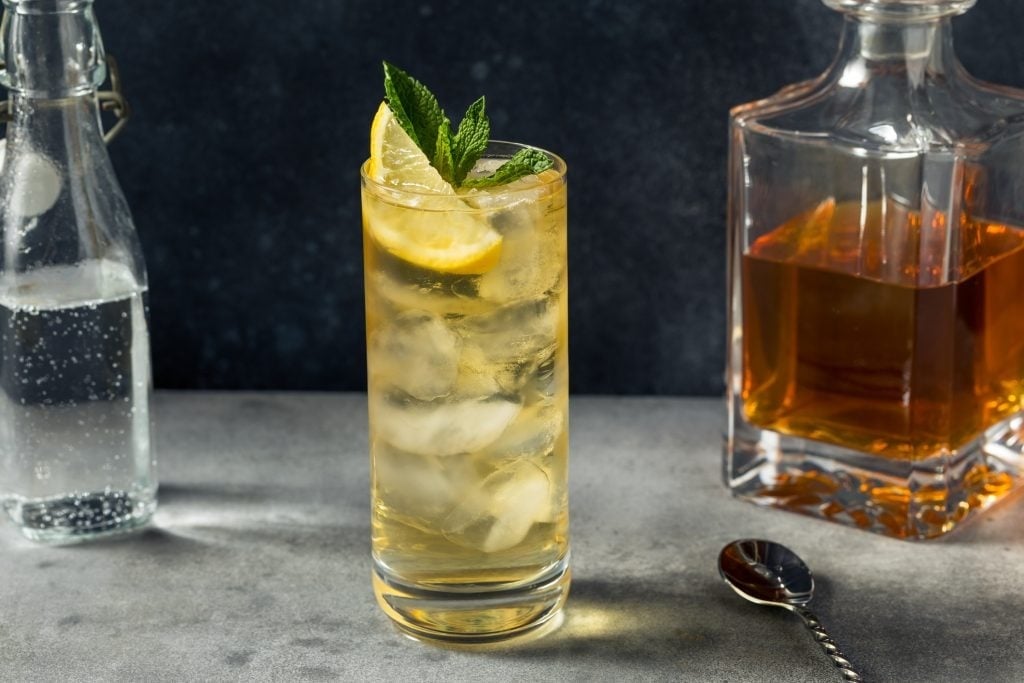 A Highball cocktail in front of a whisky decanter